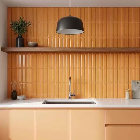 Modern kitchen walkthrough with orange kitkat wall tiles, peach laminate cabinets, and white quartz countertop