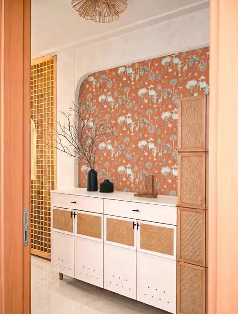 Scandinavian foyer with terracotta floral wallpaper, white cabinet, and cane panel accents