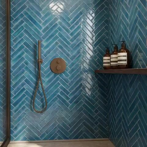 Modern bathroom walkthrough with blue herringbone subway wall tiles and matte grey floor tile