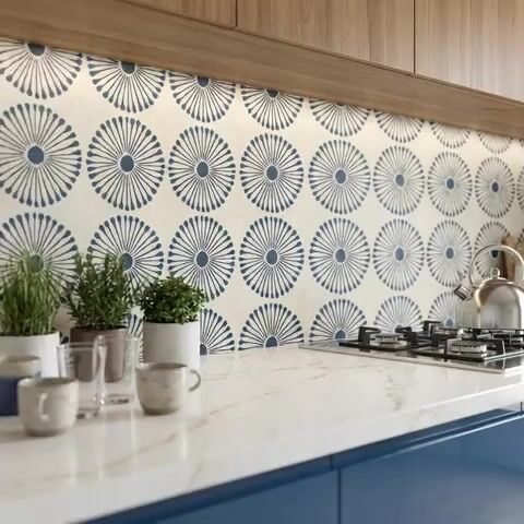 Modern kitchen walkthrough with blue geometric patterned backsplash tile, white marble-look quartz countertop, and walnut wood laminate cabinets