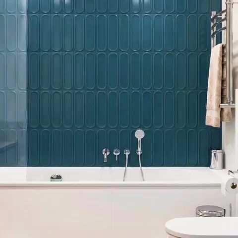 Modern bathroom walkthrough with teal elongated subway wall tiles and white bathtub