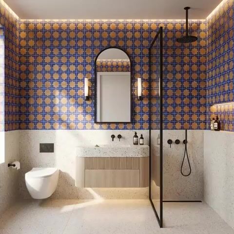 Modern bathroom walkthrough with blue and terracotta patterned wall tiles and terrazzo floor