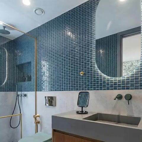 Modern bathroom walkthrough with blue mosaic wall tiles, concrete countertop, and fluted wood vanity