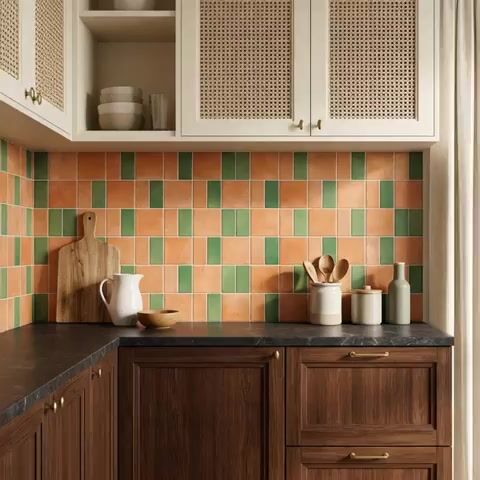 Scandinavian kitchen walkthrough with terracotta and green backsplash tiles, dark stone countertop, and wood cabinets