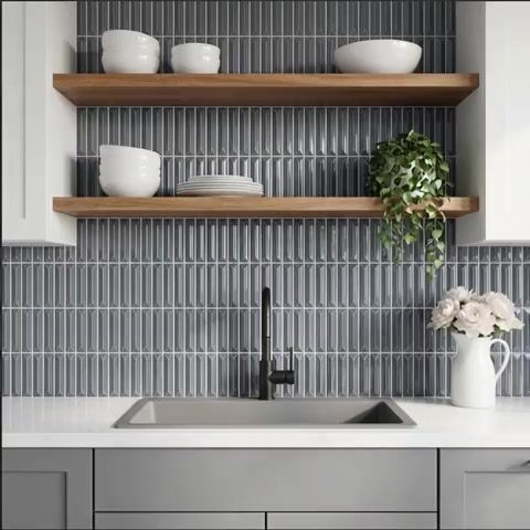 Modern kitchen walkthrough with grey geometric backsplash tile, white quartz countertop, and wooden open shelves